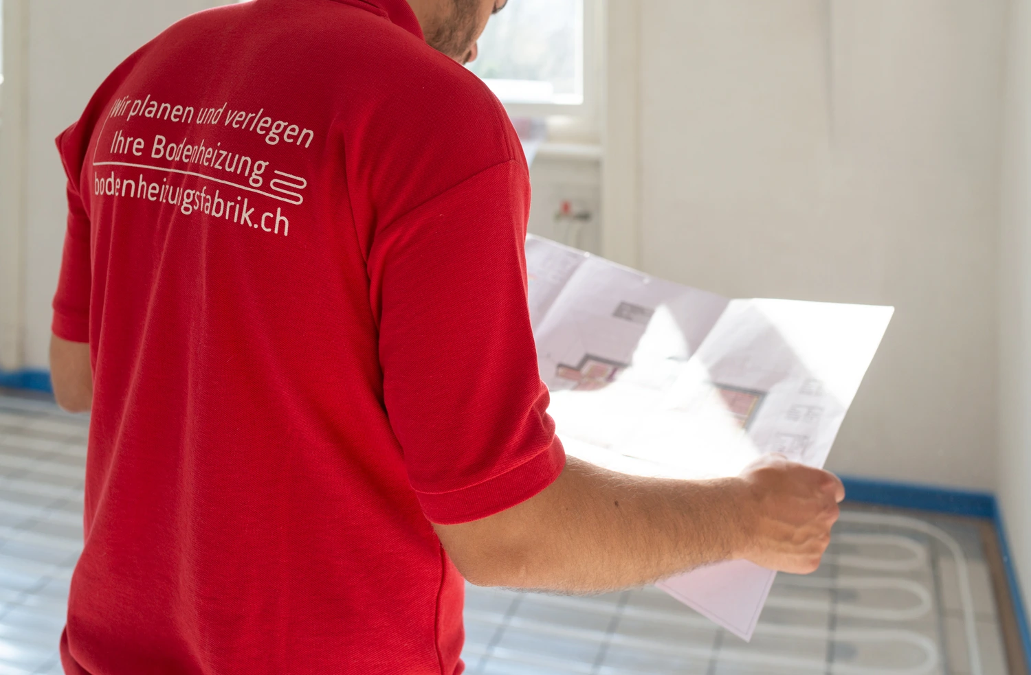 Ein Mann in einem roten Hemd hält ein Blatt Papier in der Hand.